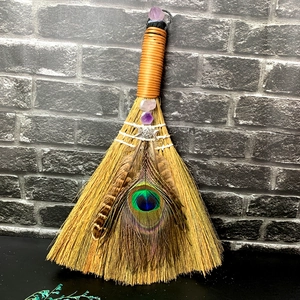 Detailed view of handmade altar broom with amethyst crystals and peacock feather