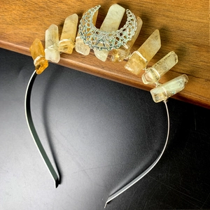 Macro detail of natural quartz crystal crown with intricate silver moon pendant carving