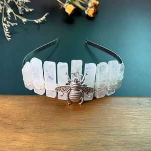 Detail of silver headband featuring raw white crystals and a metallic honeybee charm