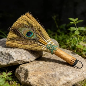 Detailed macro view of decorative ritual broom with peacock feather and bronze animal charm