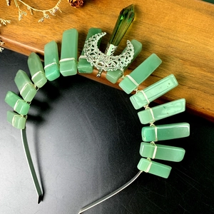 Macro detail of bohemian crown featuring green stones and silver hollow moon element