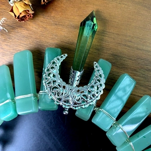 Macro detail of handmade crystal crown featuring raw green stones and hollow silver moon