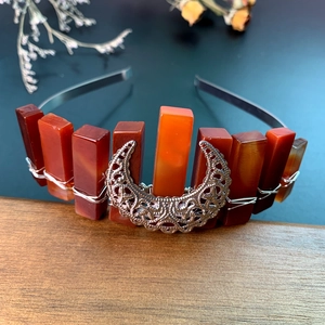 Macro detail of handmade black headband featuring orange mineral stones and silver crescent moon