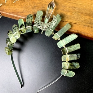 Macro detail of natural green raw crystal cluster crown with a silver crescent moon piece