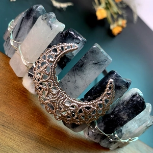 Detail of bohemian black crystal crown with silver hollow moon on a rustic wooden table