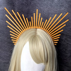 Front view of orange halo crown headband with geometric sunburst spikes on a model