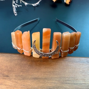 Detail of handmade orange crystal crown with silver moon on rustic wooden table