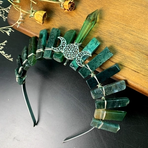 Detailed view of handcrafted crystal crown with dark green stones and silver moon detail