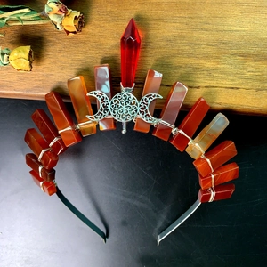 Detailed view of handmade crown featuring red crystal and triple moon metallic carving