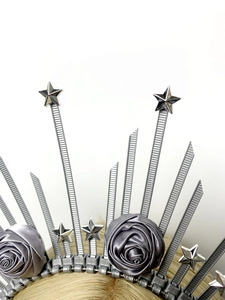 Détail d'une couronne argentée avec étoiles et roses en satin gris sur cheveux dorés