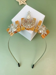 Detailed view of bohemian crown with orange raw crystals, silver bees and a central pearl