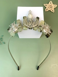 Detail of bohemian crown headband with green crystals, metal bees, and a pearl