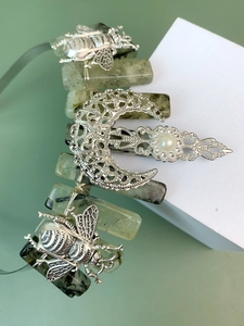 Detailed shot of green natural crystals with silver bee and moon charms on a headband