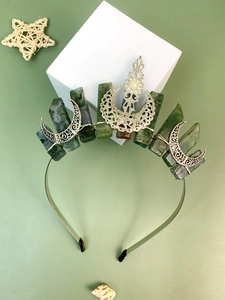 Detail of silver alloy tiara featuring green natural crystals and hollow moon ornaments