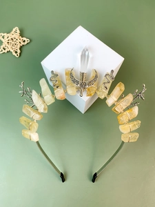 Detail of handmade crystal crown headband with moon and snake charms on green background