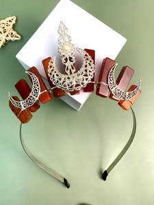 Macro detail of Bohemian crown featuring raw red crystals, silver moon, and central pearl