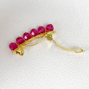 Dettaglio di fermaglio per capelli in metallo dorato con sei perle rosa sfaccettate