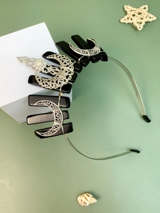 Detail of gothic crystal headband with silver crescent moons and black stones on white block
