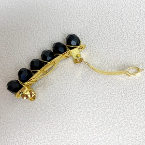 Dettaglio ravvicinato del pettine fatto a mano in filo dorato con perle di cristallo nero