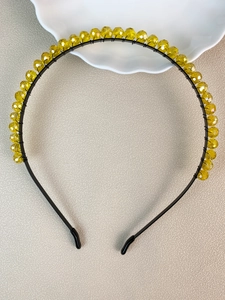 Detail of yellow faceted crystal beads hand-wired on a slim black metal bridal headband