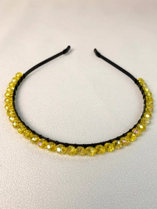 Close-up detail of handcrafted yellow faceted beads on a sleek black metal crown headband