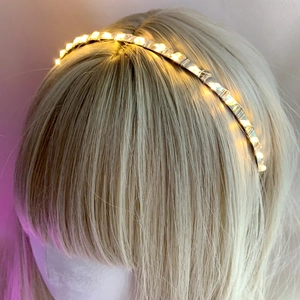 Detail shot of a slender LED headband with warm yellow starry fairy lights glowing
