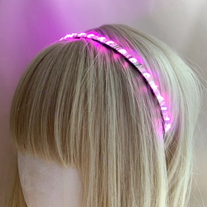 Detail of glowing pink LED headband with bright light beads on blonde hair model