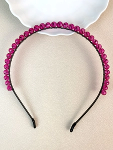 Detail of handmade beaded crown headband with magenta crystals on a black wire frame