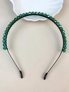 Detailed macro view of green crystal beads hand-wired on a black metal headband base
