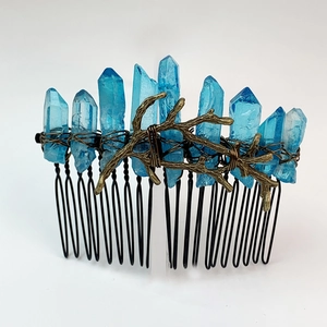 Detail of natural blue crystal hair comb with bronze metal branches on a black base
