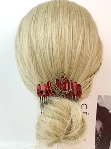 Detail view of handmade crystal hair comb with bronze moon and star charms on gold hair