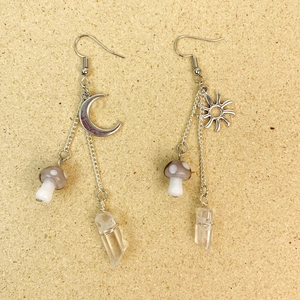 Détail macro de boucles d'oreilles bohèmes avec soleil, lune, champignon et cristaux