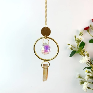 Detail of suncatcher with golden ring, rainbow crystal ball and natural stone pendant