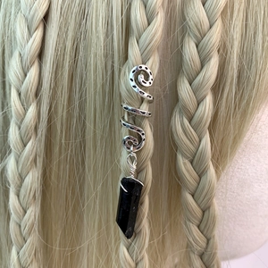 Detailed macro of vintage spiral hair ring with black crystal pendant on golden braids