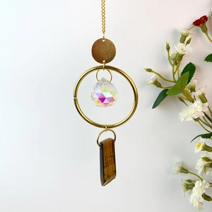 Detail of hanging crystal wind chime with gold chain, faceted ball and tiger eye stone