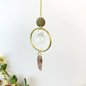 Detail of natural crystal wind chime with golden chain, crystal ball and strawberry quartz