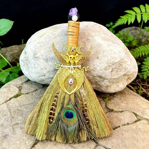 Detail of a handmade witch broom featuring natural amethyst and peacock feather decor