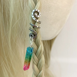 Detail of silver spiral dreadlock charm with a rainbow crystal pendant on blonde hair