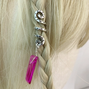 Detail of silver spiral dreadlock jewelry with pink crystal pendant on blonde braid