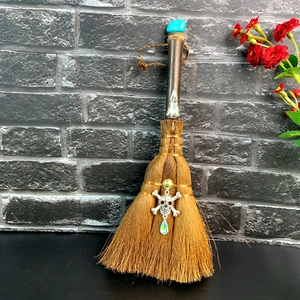 Detail of brown crystal witch broom with blue stone, skull pendant and floral accents