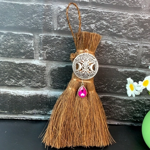 Macro detail of wicca broom charm with celtic star pentagram and pink crystal pendant