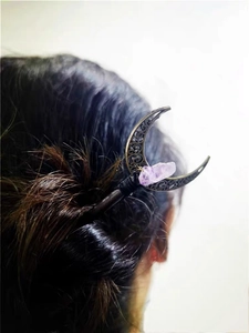 Macro view of vintage bronze crescent hair pin with natural purple crystal on female hair