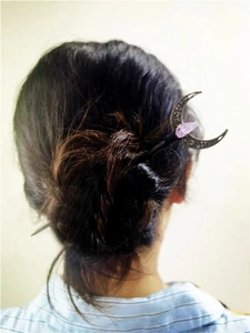 Detail of vintage bronze moon hair pin with purple crystal droplet in a hair bun