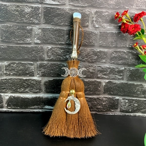 Detailed macro view of handmade witch broom with moon charm and crystal accents