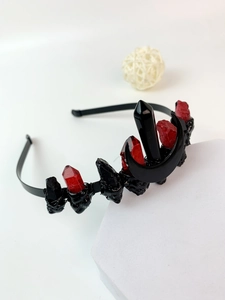 Macro detail of gothic crown headband with red crystals and black moon on white stand