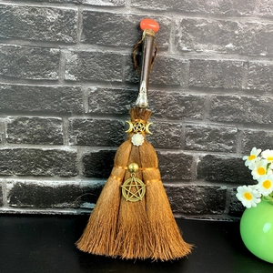 Detail of handmade brown witch broom with crystal moon charms and pearl accents
