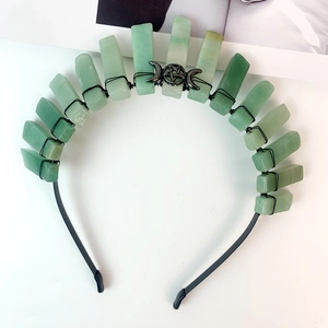 Handmade black moon crown with green raw stones and pentagram badge on white background