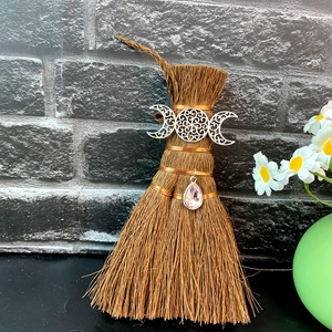 Close-up of Wicca mini broom with Triple Moon metal decor and pink crystal pendant