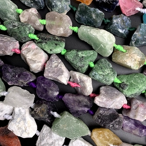 Detailed close-up of raw natural gemstone chips including amethyst and fluorite on black