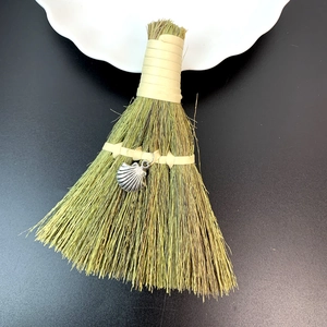 Detailed macro view of natural straw mini broom ornament with a silver shell charm detail